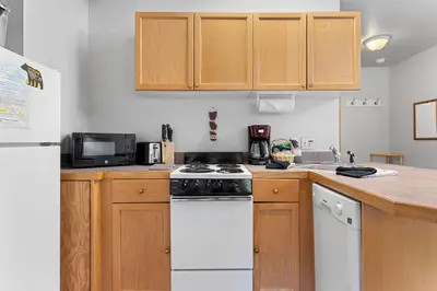 a kitchen with wooden cabinets and a white stove top oven at Creekside Suites 18 by Estes Park Condos in Estes Park