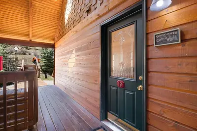 a wooden house with a green door on a wooden wall at Creekside Suites 19 by Estes Park Condos in Estes Park