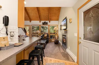 a kitchen with a bar with stools and a fireplace at Creekside Suites 19 by Estes Park Condos in Estes Park