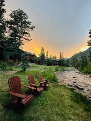 three benches sitting in the grass near a river at Bugle Pointe B23 by Estes Park Condos in Estes Park