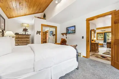 a bedroom with a large white bed and a mirror at Bugle Pointe A01 by Estes Park Condos in Estes Park