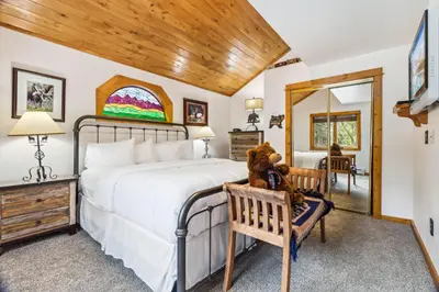 a bedroom with a large bed with a teddy bear on a chair at Bugle Pointe A01 by Estes Park Condos in Estes Park