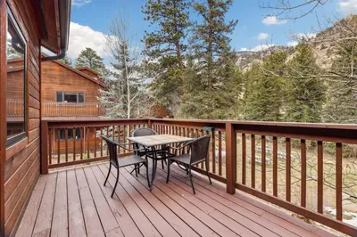 a wooden deck with a table and chairs on it at Bugle Pointe A01 by Estes Park Condos in Estes Park