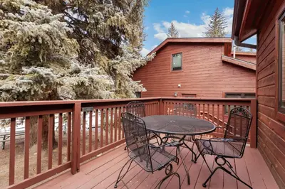 a patio with a table and chairs on a deck at Bugle Pointe A08 by Estes Park Condos in Estes Park