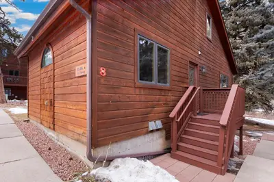 a small wooden cabin with a large deck at Bugle Pointe A08 by Estes Park Condos in Estes Park