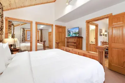 a bedroom with a large white bed and a television at Bugle Pointe A08 by Estes Park Condos in Estes Park
