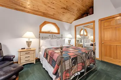 a bedroom with a bed and a chair at Bugle Pointe A11 by Estes Park Condos in Estes Park