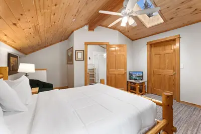 a bedroom with a large white bed and wooden ceilings at Bugle Pointe A12 by Estes Park Condos in Estes Park
