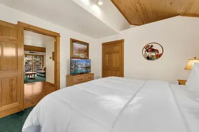 a bedroom with a large white bed and wooden cabinets at Bugle Pointe A14 by Estes Park Condos in Estes Park