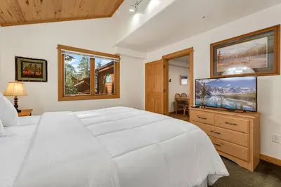a bedroom with a white bed and a flat screen tv at Bugle Pointe A14 by Estes Park Condos in Estes Park
