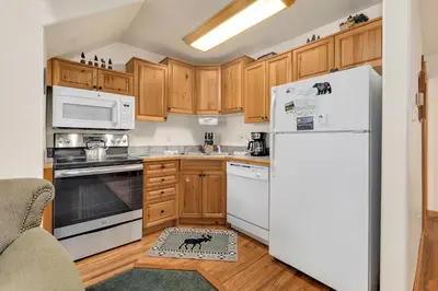 a kitchen with wooden cabinets and a white refrigerator at Bugle Pointe A14 by Estes Park Condos in Estes Park