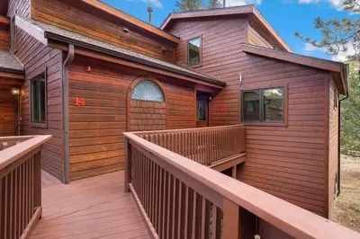 a wooden house with a deck and a door at Bugle Pointe A15 by Estes Park Condos in Estes Park