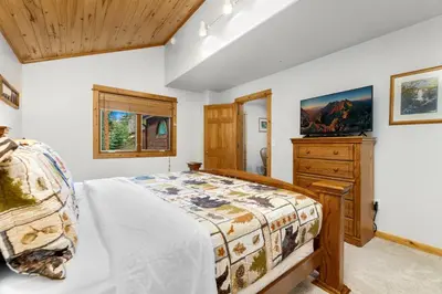 a bedroom with a bed and a wooden dresser at Bugle Pointe A15 by Estes Park Condos in Estes Park
