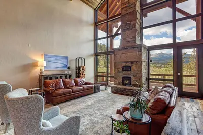 a living room with leather couches and a stone fireplace at The Observatory by Great Western Lodging in Breckenridge