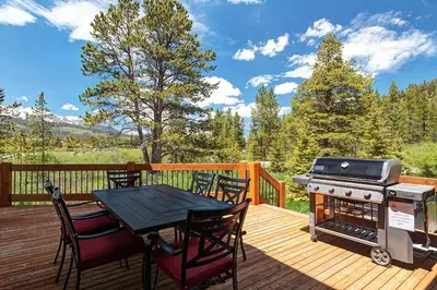 a grill on a deck with a table and chairs at The Observatory by Great Western Lodging in Breckenridge