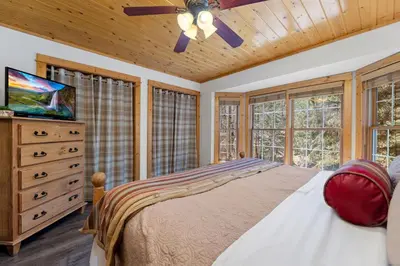 a bedroom with a bed and a tv and windows at Antlers Pointe 1 by Estes Park Condos in Estes Park