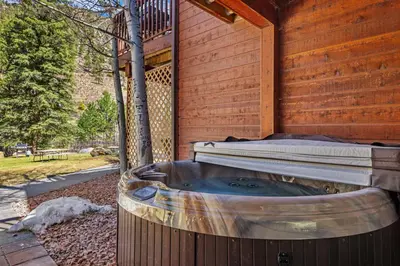 a hot tub sitting next to a wooden house at Bugle Pointe A02 by Estes Park Condos in Estes Park