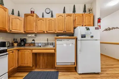 a kitchen with wooden cabinets and a white refrigerator at Bugle Pointe A02 by Estes Park Condos in Estes Park