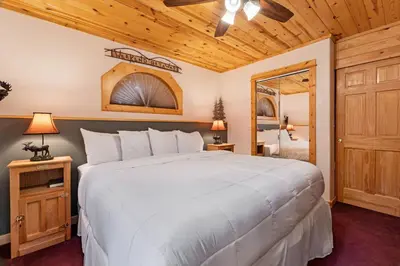 a bedroom with a large white bed and a mirror at Bugle Pointe B10 by Estes Park Condos in Estes Park