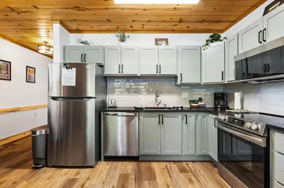 a kitchen with white cabinets and a stainless steel refrigerator at Bugle Pointe B12 by Estes Park Condos in Estes Park