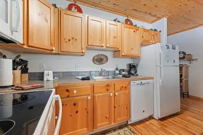 a kitchen with wooden cabinets and a white refrigerator at Bugle Pointe B18 by Estes Park Condos in Estes Park