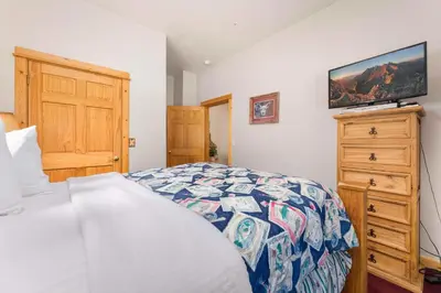 a bedroom with a bed and a dresser with a tv at Bugle Pointe A16 by Estes Park Condos in Estes Park