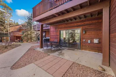 a patio with a table and chairs next to a building at Bugle Pointe B20 by Estes Park Condos in Estes Park
