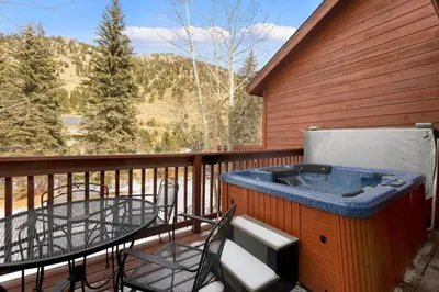 a hot tub on a deck with a table and chairs at Bugle Pointe A03 by Estes Park Condos in Estes Park