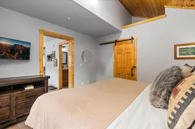a bedroom with a bed and a wooden cabinet at Bugle Pointe B13 by Estes Park Condos in Estes Park
