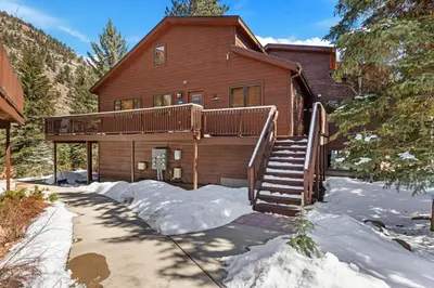 a large wooden house with a staircase in the snow at Bugle Pointe B21 by Estes Park Condos in Estes Park