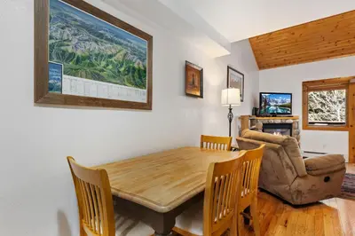 a dining room with a wooden table and a couch at Bugle Pointe B21 by Estes Park Condos in Estes Park