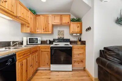 a kitchen with wooden cabinets and a black and white stove at Creekside Condos D by Estes Park Condos in Estes Park