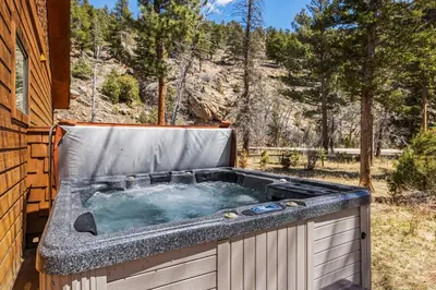 a hot tub sitting on the side of a house at Creekside Condos H by Estes Park Condos in Estes Park