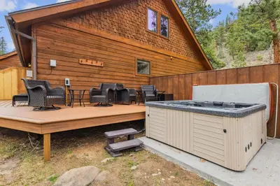 a house with a deck with chairs and a hot tub at Creekside Condos H by Estes Park Condos in Estes Park