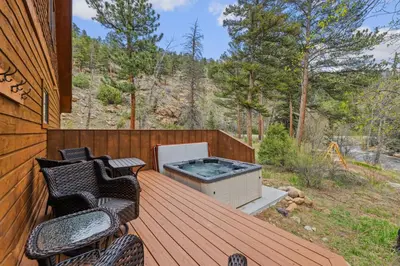 a deck with a hot tub and two chairs at Creekside Condos H by Estes Park Condos in Estes Park