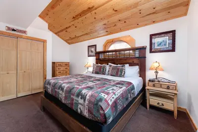 a bedroom with a bed with a wooden headboard at Bugle Pointe B15 by Estes Park Condos in Estes Park