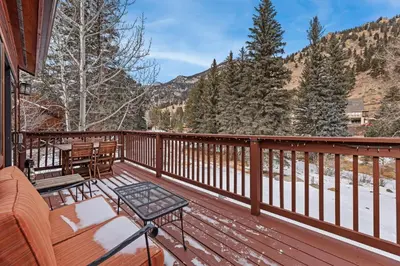 a deck with a couch and a table and chairs at Bugle Pointe A04 by Estes Park Condos in Estes Park
