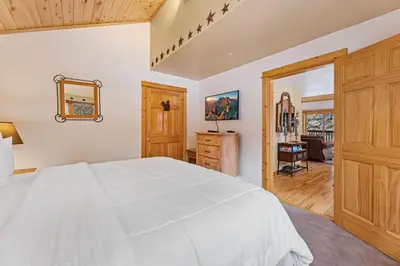 a bedroom with a white bed and a wooden closet at Bugle Pointe A04 by Estes Park Condos in Estes Park