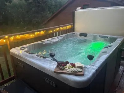 a hot tub with two glasses of wine and a plate of food at Bugle Pointe A04 by Estes Park Condos in Estes Park