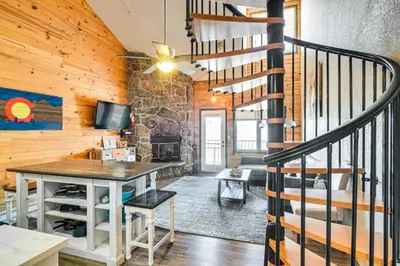 a living room with a staircase and a stone wall at Hot Tub and Indoor Pool Access at Granby Condo in Granby