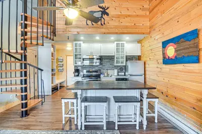 a kitchen with a table and stools in a room at Hot Tub and Indoor Pool Access at Granby Condo in Granby