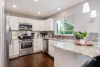 a kitchen with white cabinets and stainless steel appliances at Mid-Mod Marvel Central Game RmWet Bar Patio in Arvada