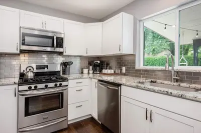 a kitchen with white cabinets and stainless steel appliances at Mid-Mod Marvel Central Game RmWet Bar Patio in Arvada