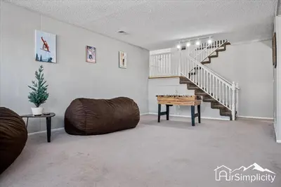 a living room with a staircase and a couch and a table at Spacious home w game room & firepit in Arvada