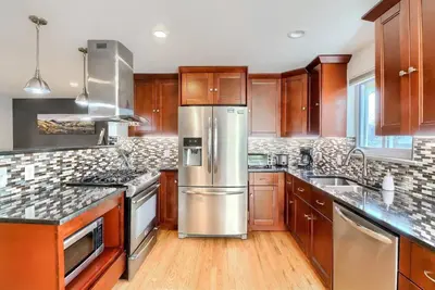 a kitchen with wooden cabinets and stainless steel appliances at Group-Friendly 4-Bedroom Denver Home w Backyard in Centennial