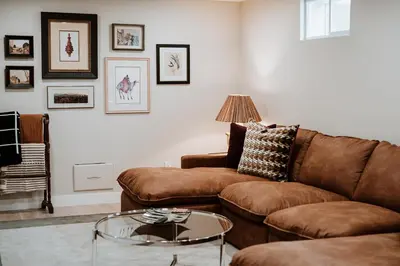 a living room with a brown couch and a glass table at Modern home w hot tub & game room in Centennial