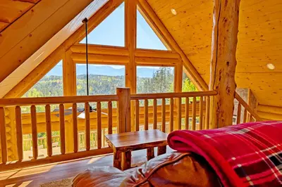 a room with a table and a large window in a cabin at New Log Home, Hot Tub For 8, Views! in Tabernash