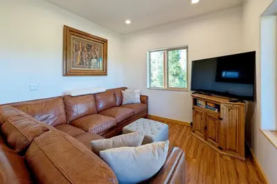 a living room with a brown leather couch and a flat screen tv at New Log Home, Hot Tub For 8, Views! in Tabernash