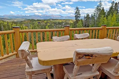 a wooden table and chairs on a deck with a view at New Log Home, Hot Tub For 8, Views! in Tabernash