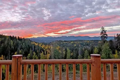 a sunset from a deck with a view of the mountains at New Log Home, Hot Tub For 8, Views! in Tabernash